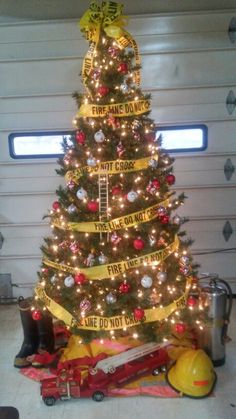 a christmas tree decorated with yellow ribbon and fireman's gear is in front of a garage door