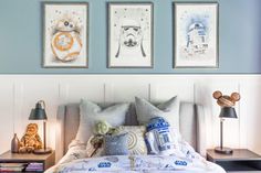 a bed with two star wars pictures on the wall above it and a lamp next to it