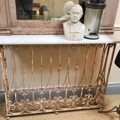 an antique console table with a busturine on top and a mirror behind it