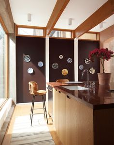 a kitchen with wooden cabinets and counter tops next to a window filled with vases