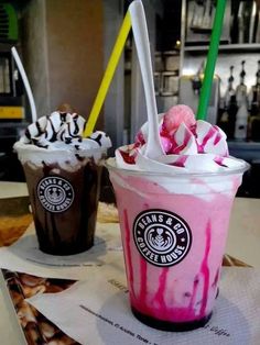 two drinks sitting on top of a table next to each other with straws in them