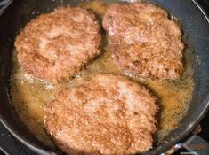 three fried meat patties cooking in a frying pan on the stove with oil