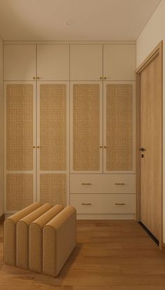 an empty room with wooden flooring and beige furniture on the wall, next to a closet