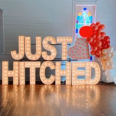 a lighted sign that says just hitched with balloons in the shape of heart and letters