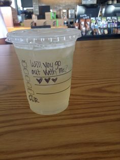 a plastic cup with writing on it sitting on a wooden table next to a bar