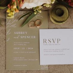 the wedding stationery is laid out on the floor with two gold rings and flowers