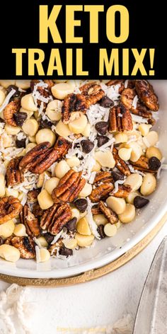 a white bowl filled with nuts and cheese on top of a table next to a fork