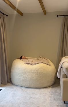 a woman is sleeping on a bean bag chair in the middle of a living room