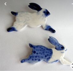 two blue and white ceramic rabbits sitting on top of each other