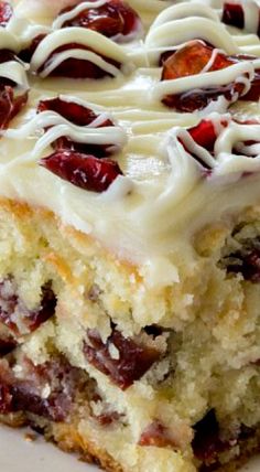 a piece of cake with white frosting and cranberries on it sitting on a plate