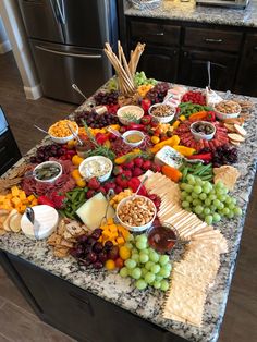 a table full of cheese, crackers, grapes and other foods on top of it