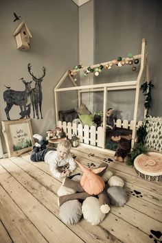 a child is sitting on the floor in front of a doll house and stuffed animals