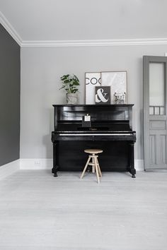 a black piano sitting in the corner of a room next to a chair and potted plant