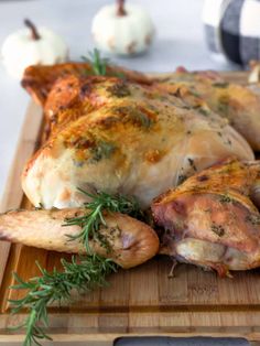 a whole chicken on a cutting board with garlic and rosemary sprigs next to it