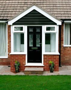 a black front door on a brick house with two planters in the foreground