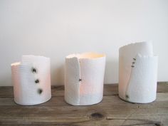 three white vases sitting on top of a wooden table