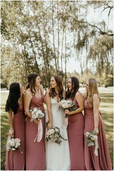 a group of women standing next to each other wearing dresses and holding bouquets in their hands