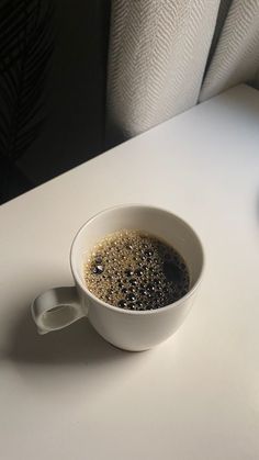 a cup of coffee sitting on top of a white table