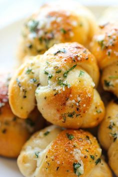 small rolls covered in cheese and herbs on top of a white plate with parmesan sprinkles