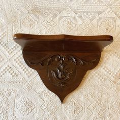 an ornate wooden shelf on top of a white bedspread