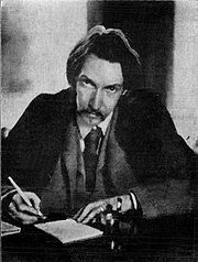 an old photo of a man sitting at a desk with a pen and paper in his hand