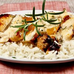 a white plate topped with rice and chicken on top of a red table cloth next to a fork