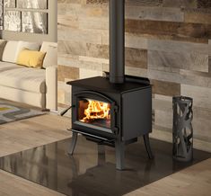 a wood burning stove in a living room next to a white couch and wooden wall