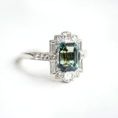 Item Details: One color change blue-green emerald cut sapphire weighing approx. 3.58 ctw. Twenty-two natural carré, baguette, and round brilliant cut diamonds weighing approx. 0.75 ctw, G color VS clarity. Set in platinum. This ring was custom created with one-of-a-kind stones. Email custom@berlingerrings.com to create a similar ring. Enquire Design a custom piece with us Art Deco Engagement Ring Emerald, Berlinger Jewelry, Emerald Ring White Gold, Art Deco Sapphire Engagement Ring, Change Blue, Emerald Cut Sapphire Ring, Sapphire Engagement Ring Halo, Asscher Cut Engagement Rings, Art Deco Emerald Ring