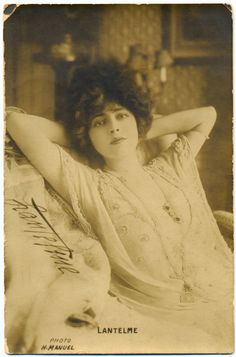 an old black and white photo of a woman sitting on a couch with her hands behind her head