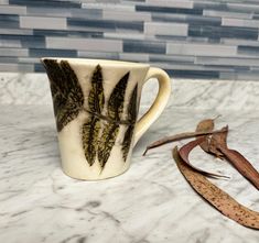 a coffee cup sitting on top of a marble counter next to a pair of scissors