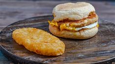 an egg sandwich and fried fish on a wooden plate