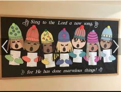 a group of children's handmade paper hats hanging on a wall above a sign that says sing to the lord a new song for he has done marvelous things