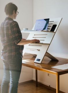 a person standing in front of a desk with a laptop on it