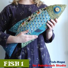 a woman is holding a fish pillow in her hands