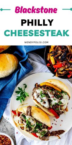 two cheese steak sandwiches on a white plate with blue napkins and other food items