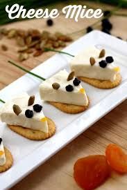 small crackers with cream cheese and black olives are on a white platter