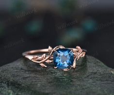 an engagement ring with a blue topazte surrounded by leaves