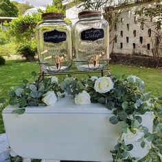 two mason jars sitting on top of a table with greenery around them and flowers