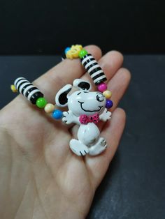 a hand holding a small toy dog with beads on it