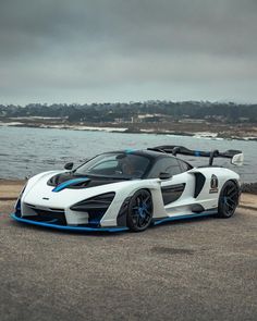 a white and blue sports car sitting on top of a road next to the ocean