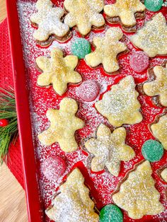 a red tray filled with christmas cookies on top of a wooden table