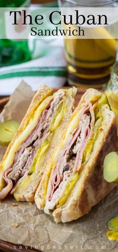 a sandwich cut in half sitting on top of a cutting board next to pickles