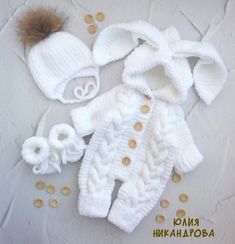 a white knitted baby outfit and hat with pom - pom on top