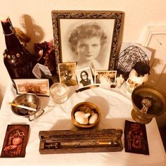 a table topped with pictures and other items on top of a white cloth covered table