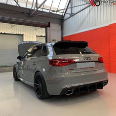 the rear end of a grey car parked in a garage