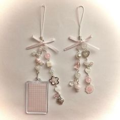 two tags with charms attached to them sitting on a table next to each other in front of a white background