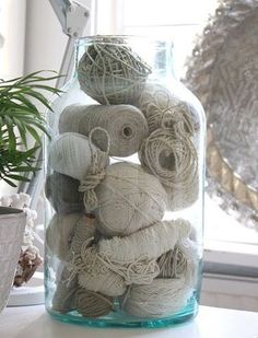 a glass jar filled with yarn next to a potted plant