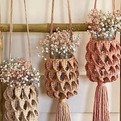 three vases with flowers are hanging on the wall and one is made out of rope