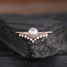 a pearl and diamond ring sitting on top of a rock