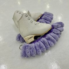 two pairs of shoes with fuzzy purple and white laces sitting on top of each other